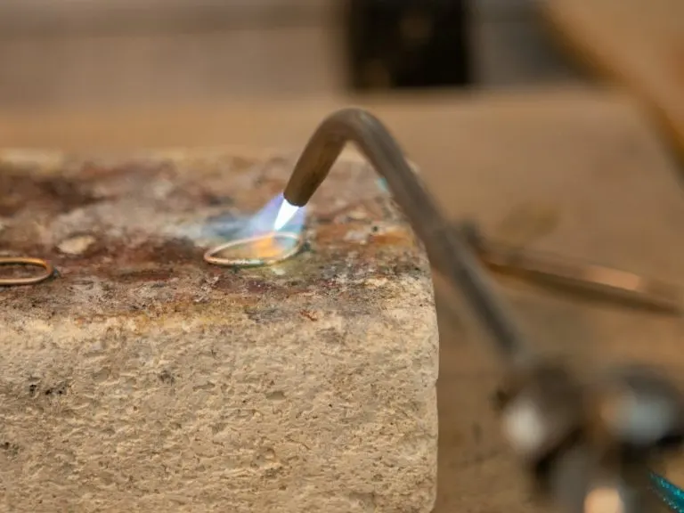Silversmith soldering a handmade silver ring with a torch during a silver class in Sanur, Bali